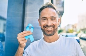 Mężczyzna w prawej dłoni trzyma niebieską wstążkę – symbol raka prostaty