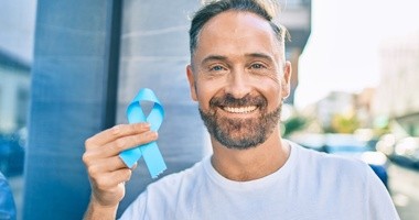Mężczyzna w prawej dłoni trzyma niebieską wstążkę – symbol raka prostaty