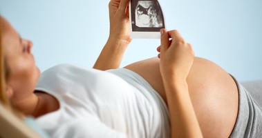 Kobieta w ciąży ogląda zdjęcie USG dziecka