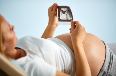 Kobieta w ciąży ogląda zdjęcie USG dziecka