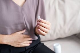 Bifidobacterium, probiotyki z bifidobakteriami, działanie bifidobakterii, kobieta przyjmuje kapsułkę z probiotykiem