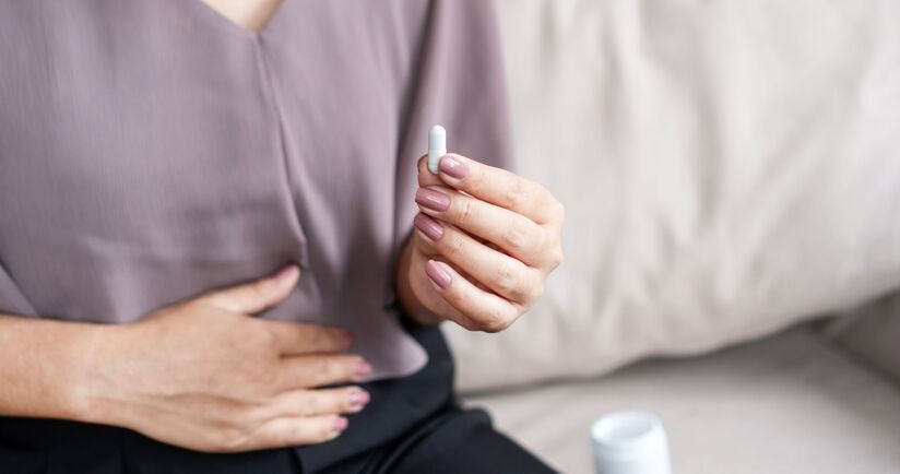 Bifidobacterium, probiotyki z bifidobakteriami, działanie bifidobakterii, kobieta przyjmuje kapsułkę z probiotykiem