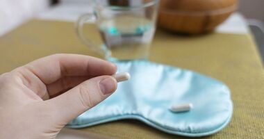 tabletka z melatoniną w dłoni i opaska na oczy, jak dawkować melatoninę na sen, suplementacja melatoniny, wpływ melatoniny na sen