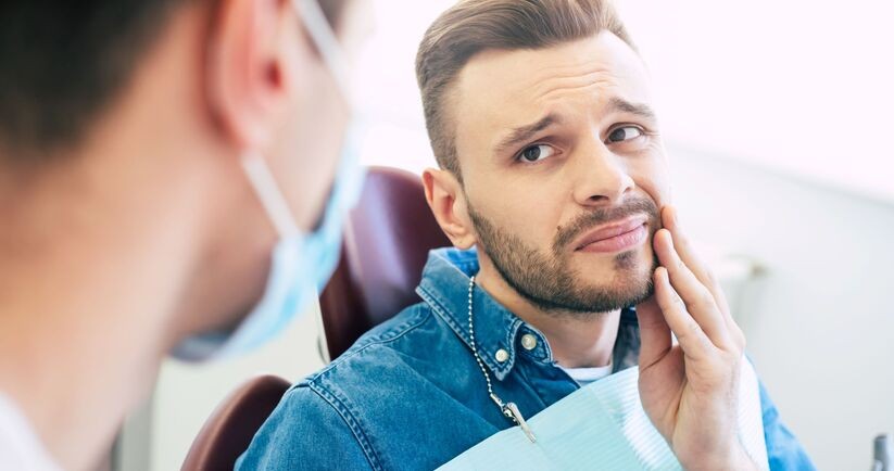 pacjent na fotelu stomatologicznym, czuje ból zęba