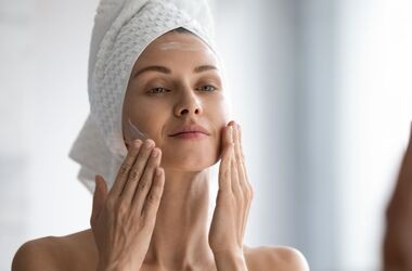 cera mieszana, pielęgnacja cery mieszanej, kobieta nakłada krem przed lustrem