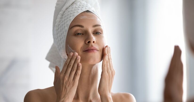 cera mieszana, pielęgnacja cery mieszanej, kobieta nakłada krem przed lustrem