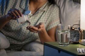 kobieta zażywająca tabletkę,  jak dawkować melatoninę na sen, suplementacja melatoniny, wpływ melatoniny na sen