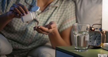kobieta zażywająca tabletkę,  jak dawkować melatoninę na sen, suplementacja melatoniny, wpływ melatoniny na sen