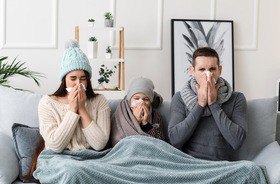 Rodzna chora na grypę siedzi na szarej kanapie