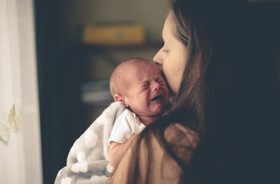 Matka trzyma na rękach placzące niemowle