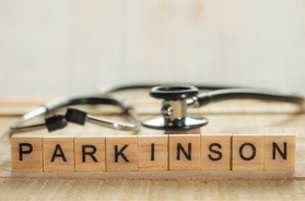 Literki ułożone w słowo Parkinson, za którymi lezy stetoskop lekarski