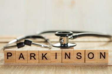 Literki ułożone w słowo Parkinson, za którymi lezy stetoskop lekarski