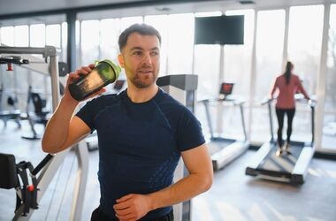 mężczyzna na siłowni, trzymający shaker w dłoni, suplementacja eaa, eaa a bcaa, aminokwasy eaa