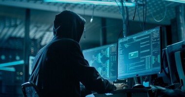 Haker siedzi przy komputerze i dokonuje wycieku danych