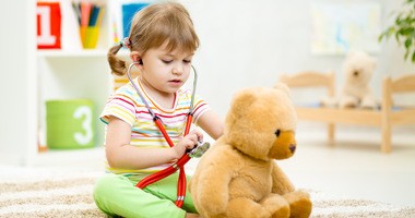 Dziecko bawi się w lekarza z pluszowym misiem, używając stetoskopu