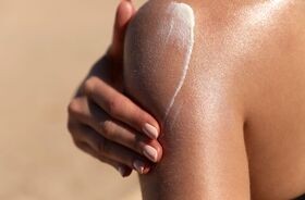 utrwalanie opalenizny, jak utrwalić opaleniznę, opalona kobieta nakłada spf na ramię