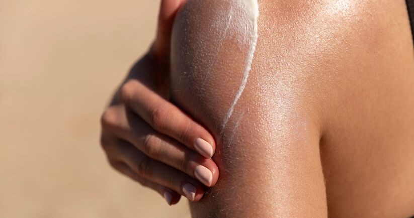 utrwalanie opalenizny, jak utrwalić opaleniznę, opalona kobieta nakłada spf na ramię