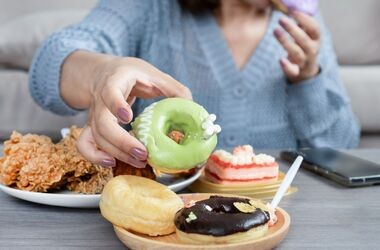 ochota na coś słodkiego, łaknienie cukru, kobieta sięga po pączka do talerza z wypiekami