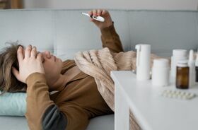 wzrost zakażeń grypą, zachorowania na grypę, szczyt zachorowań na grypę w Polsce, kobieta chora na grypę mierzy temperaturę