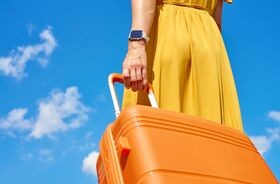 przewóz leków za granicę, leki a zagraniczne wakacje, zmiana przepisów przewóz leków, kobieta w żółtej sukience z pomarańczową walizką