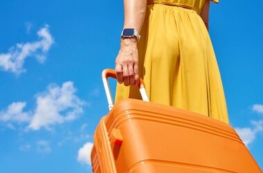 przewóz leków za granicę, leki a zagraniczne wakacje, zmiana przepisów przewóz leków, kobieta w żółtej sukience z pomarańczową walizką