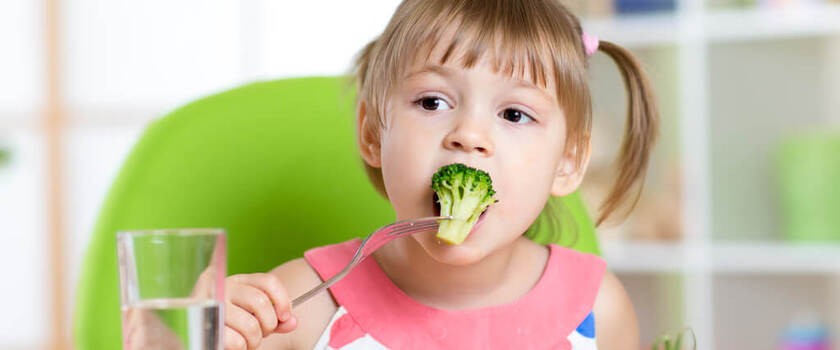 Dziewczynka ze smakiem zajada brokuła
