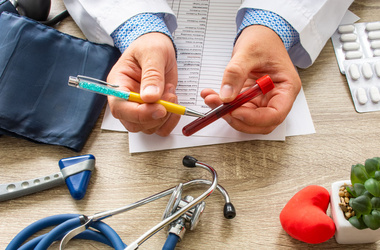 lekarz trzymający probówkę z krwią i tłumaczący co to jest anemia