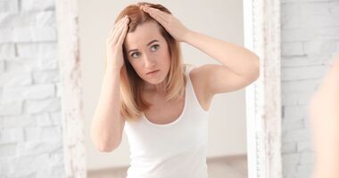 kobieta z łysieniem plackowatym przegląda się w lustrze, pielęgnacja przy łysieniu plackowatym, pielęgnacja włosów przy alopecia areata