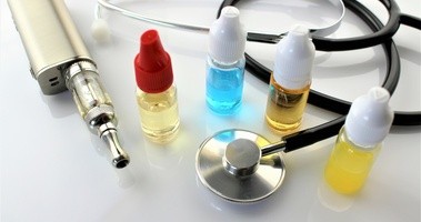 Liqudiy do e-papierosów i stetoskop leżą na białym blacie