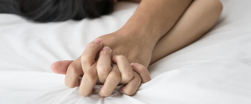Złączone dłonie kochanków w czasie seansu miłości zwieńczonego orgazmem wielokrotnym