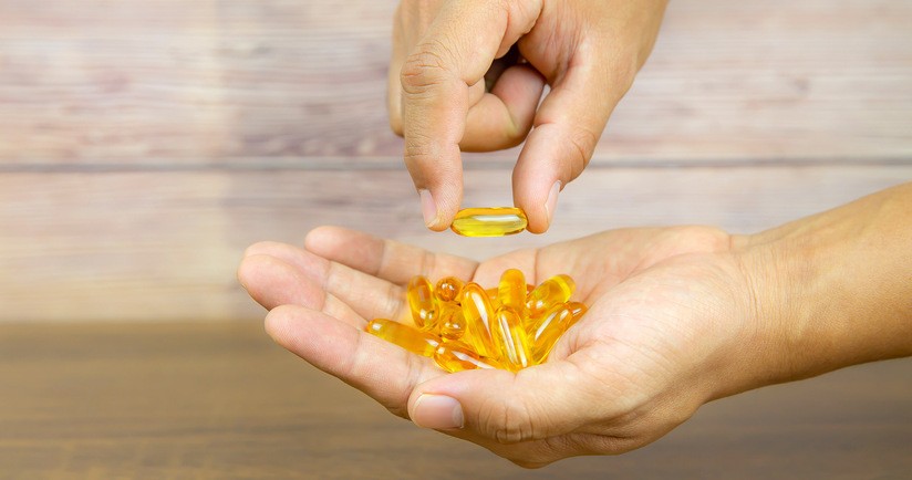 Kapsułki tranu na dłoni. Tran, tran z wątroby dorsza, tran w kapsułkach, właściwości tranu, tran na odporność.