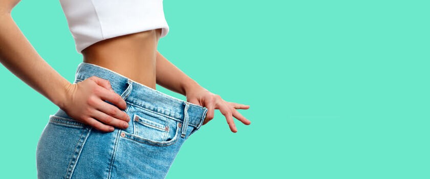 Kobieta pokazująca swoje stare spodnie po zrzuceniu wagi
