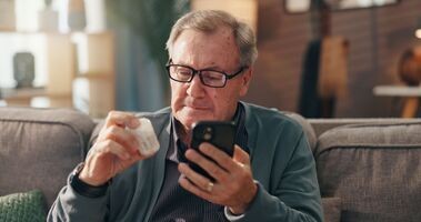 starszy mężczyzna z lekiem i telefonem w ręku, nowa lista leków refundowanych