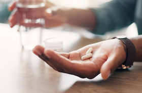 alergia na leki, objawy alergii na leki, męska ręka z tabletką do połknięcia