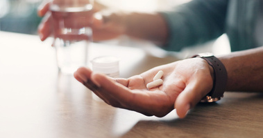 alergia na leki, objawy alergii na leki, męska ręka z tabletką do połknięcia