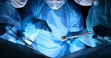 Grupa chirurgów w maskach wykonujących operację. Fluorescencja w chirurgii i pomocy w nagłych wypadkach