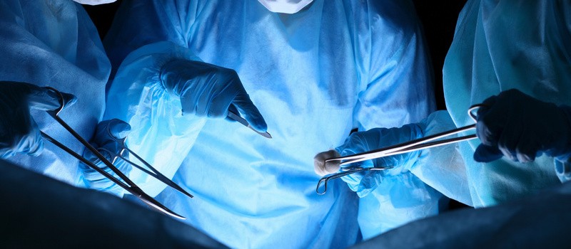 Grupa chirurgów w maskach wykonujących operację. Fluorescencja w chirurgii i pomocy w nagłych wypadkach