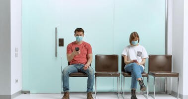 Ludzie siedzący w kolejce u lekarza na korytarzu