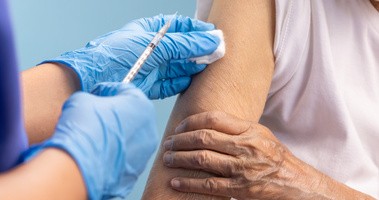 Medyk szczepi starszą osobę. Rekordowa liczba szczepień przeciwko grypie.