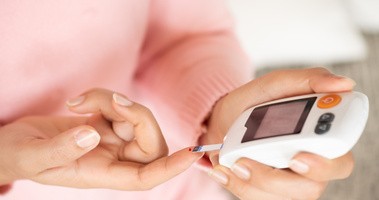 Kobieta sprawdza poziom cukru we krwi glukometrem