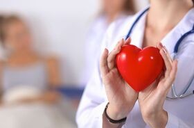 Lekarka trzymająca w dłoniach plastikowe serca. Klopidogrel czy aspiryna?
