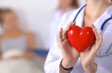 Lekarka trzymająca w dłoniach plastikowe serca. Klopidogrel czy aspiryna?