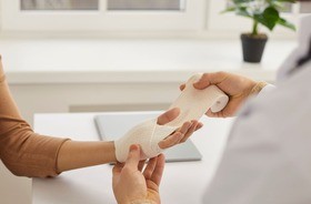 Medyk zakładający opatrunek na dłoń pacjentki. Rodzaje ran, rany.