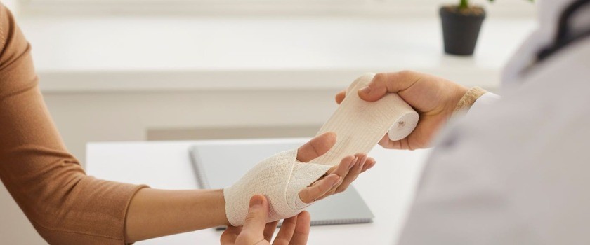 Medyk zakładający opatrunek na dłoń pacjentki. Rodzaje ran, rany.