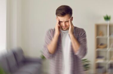 zapalenie opon mózgowo-rdzeniowych, mężczyzna trzymający się za głowę, objawy zapalenia opon mózgowo-rdzeniowych