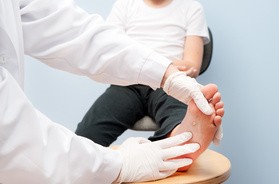 Pacjent z kurzajką na stopie jest badany przez lekarza dermatologa