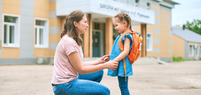 Dziecko wraz z mamą pierwszego dnia w przedszkolu, stoją przed budynkiem przedszkola i żegnają się