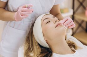 zabiegi kosmetyczne zimą, jakie zabiegi wykonywać zimą, kobieta podczas zabiegu u kosmetologa, pielęgnacja twarzy zimą