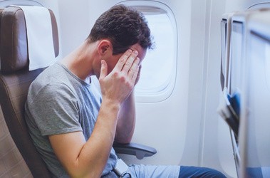 Zmęczony mężczyzna przeżywa jet lag podczas lotu w samolocie