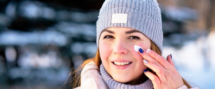 zimowa pielęgnacja, pielęgnacja skóry zimą, kremy na mróz, kremy na zimę, kobieta smaruje twarz kremem na mrozie